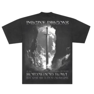 The back of the black Imagine Dragons Hollywood Bowl T-shirt features a dramatic grayscale design of a sword standing upright between rocky cliffs, illuminated by light from above. "Imagine Dragons" is printed at the top, with "Hollywood Bowl" and event details below, celebrating their live performance with the LA Film Orchestra.