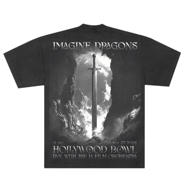 The back of the black Imagine Dragons Hollywood Bowl T shirt features a dramatic grayscale design of a sword standing upright between rocky cliffs illuminated by light from above Imagine Dragons is printed at the top with Hollywood Bowl and event details below celebrating their live performance with the LA Film Orchestra