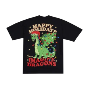 A black T-shirt featuring a large, colorful holiday-themed graphic on the back. The design showcases a cheerful green dragon wearing a red Santa hat, wrapped in multicolored Christmas lights. Above the dragon, the text "HAPPY HOLIDAYS" is written in bold, festive font, while below it, "From IMAGINE DRAGONS" appears in red. Small snowflakes are scattered around the design, adding to the holiday theme.