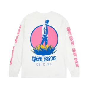 White long sleeve Imagine Dragons Origins tour shirt featuring a stylized graphic of a person standing on a large plant with a pink circular backdrop The bands name Imagine Dragons appears in bold blue text below the design with Origins written underneath in a smaller font The sleeves have repeating pink Imagine Dragons text along their length